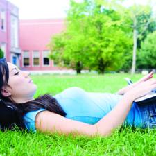 female college student on laptop outdoors