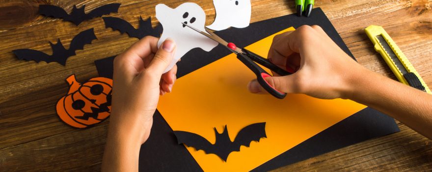 Hand's holding scissors cutting out Halloween images.