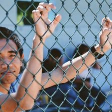 young man grabbing chain link fence