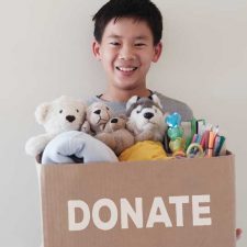 child holding box of donations for charity