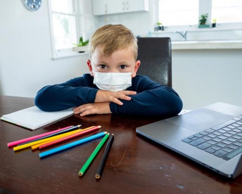 kid in face mask at homework station