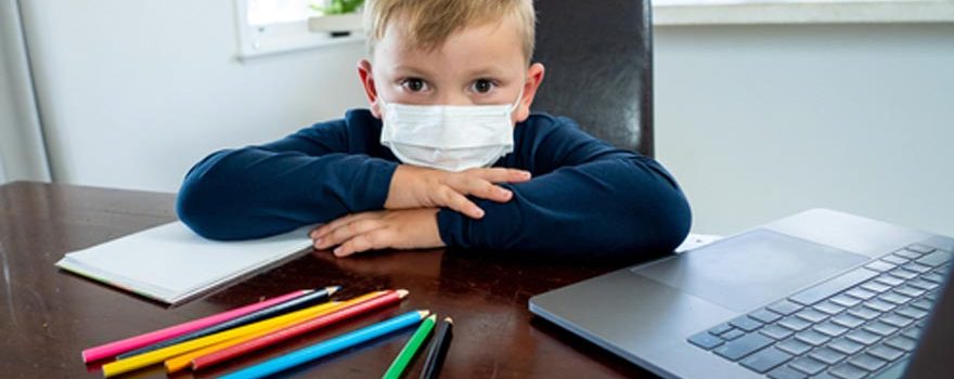 kid in face mask at homework station