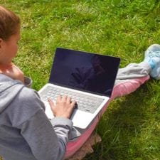 girl using laptop in grass