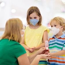 kids with face masks sanitizing
