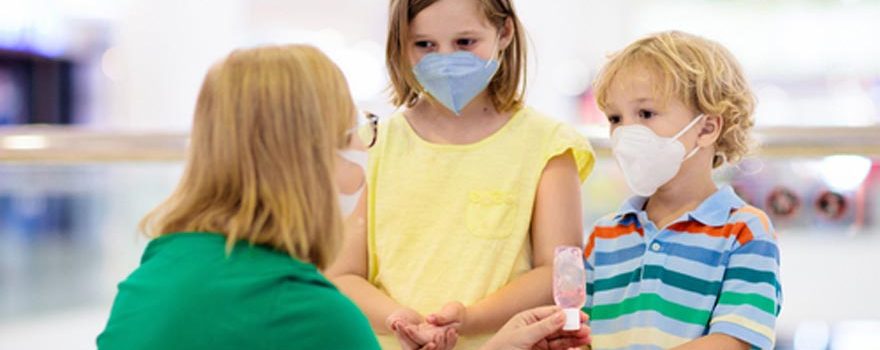 kids with face masks sanitizing