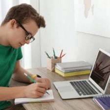 Teenage boy does schoolwork at his desk