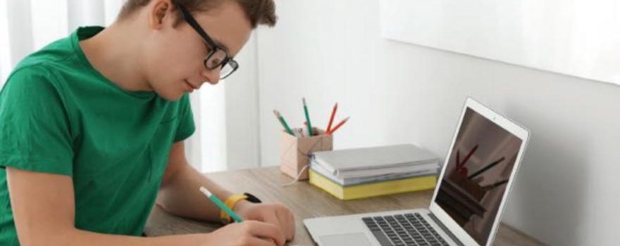 Teenage boy does schoolwork at his desk