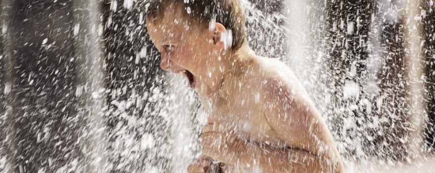 kid playing in sprinkler