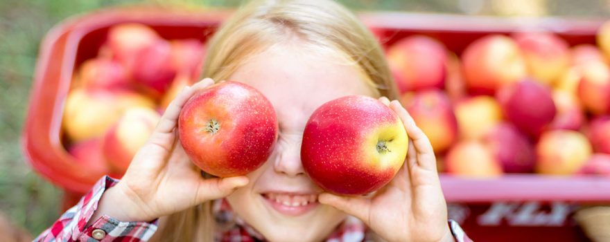 Girl holds apples in front of her eyes