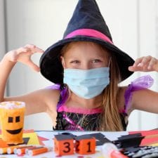 Girl with mask wearing witch costume having Halloween fun