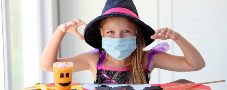 Girl with mask wearing witch costume having Halloween fun