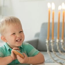 Toddler smiles at menorah on Hanukkah