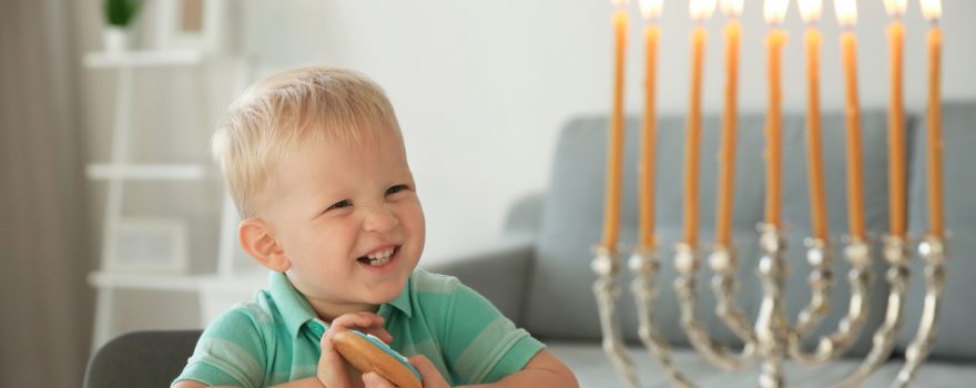 Toddler smiles at menorah on Hanukkah