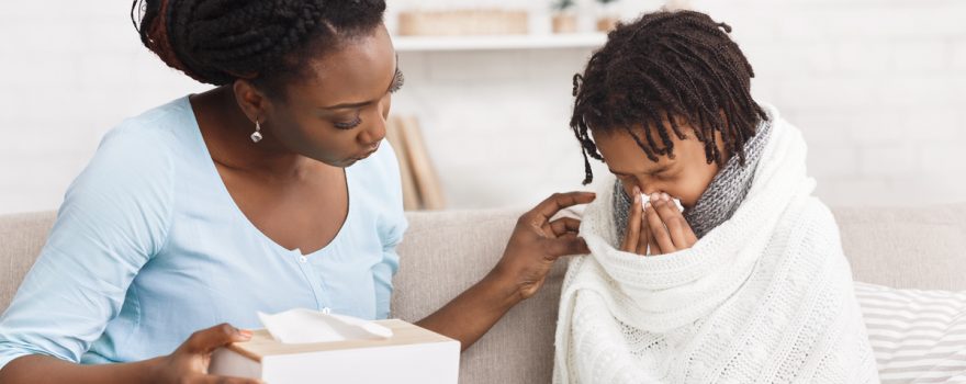 Sick child blows nose next to mom