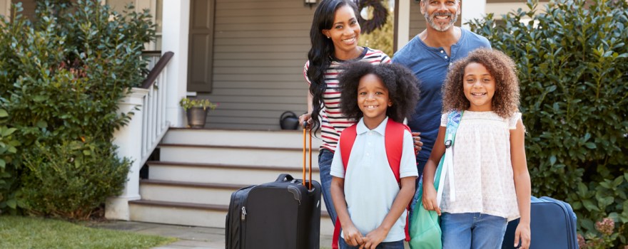 family with suitcases outside their home