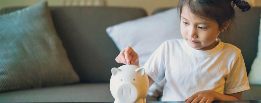 young girl saving money in piggy bank