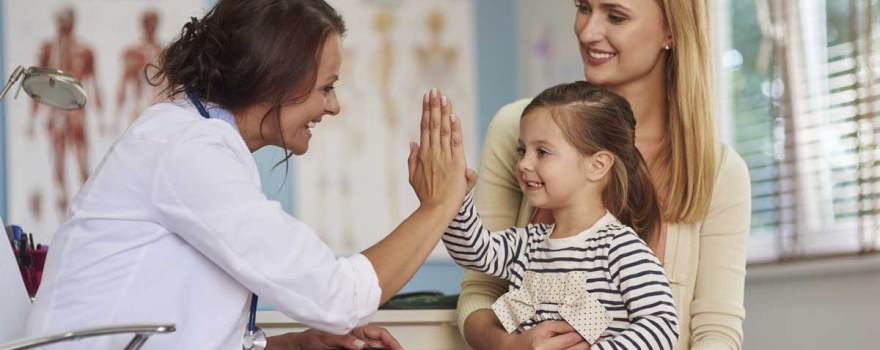 child giving pediatrician high-five while parent asks questions