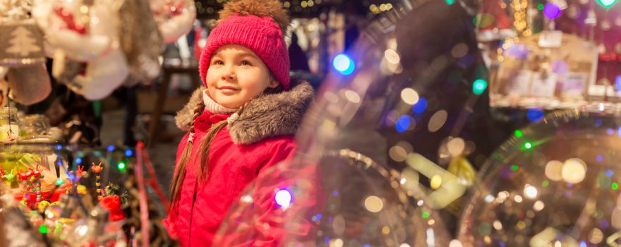 girl in winter coat surrounded by holiday ornaments