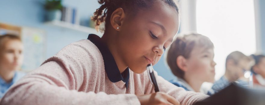 young girl writing in classroom