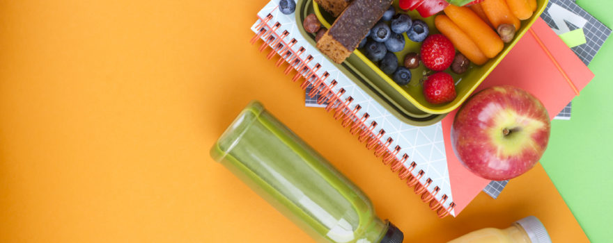 a lunchbox of sliced fruit on top of notebooks