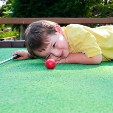 Young boy playing mini golf