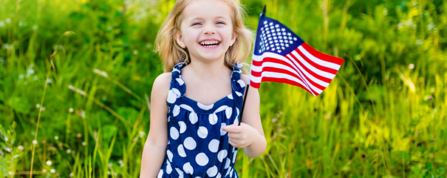 little girl holding an American flag in the summertime
