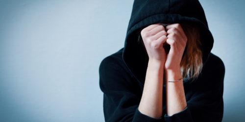 Young girl hiding her face under hooded sweatshirt