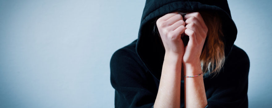 Young girl hiding her face under hooded sweatshirt