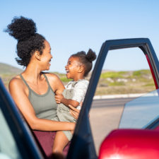 mother and young daughter next to a car