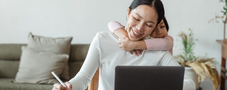 Family caregiver with a young child at a laptop.