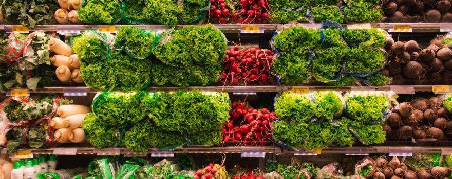 Groceries, specifically produce, on shelves in a store.