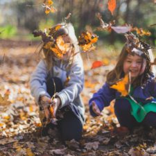 Kids playing with leaves on a hiking trail to show first-day hikes on Staten Island.