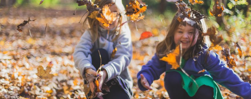 Kids playing with leaves on a hiking trail to show first-day hikes on Staten Island.