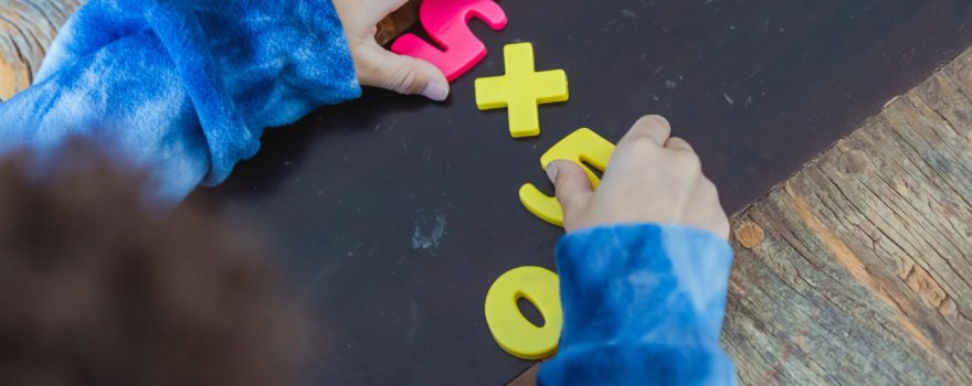 Toddler playing with toy numbers in preschool.