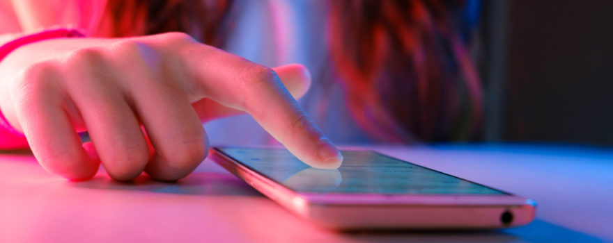 Hand of teen girl scrolling on a phone.