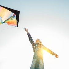 Child flying a kite outdoors on a sunny day. Many kite festivals in New York and New Jersey let people fly kites.