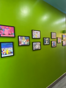 Colorful artwork hanging on a wall by Michael J. Petrides School students.