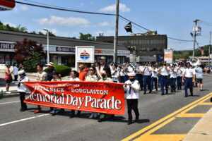 Parade marchers holding a sign the reads Little-Neck Douglaston Memorial Day Parade. 