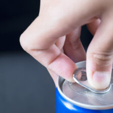 A person's hand opening a can. Prime energy drink is available in a similar can