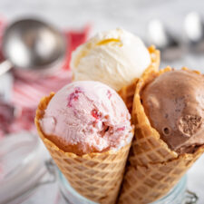 three ice cream cones with vanilla, chocolate and strawberry ice cream scoops. National Ice Cream Day is July 16 this year.