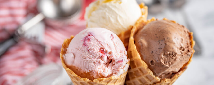three ice cream cones with vanilla, chocolate and strawberry ice cream scoops. National Ice Cream Day is July 16 this year.