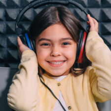 a little girl wearing headphones during a hearing test, which is a way of detecting and preventing hearing loss in children