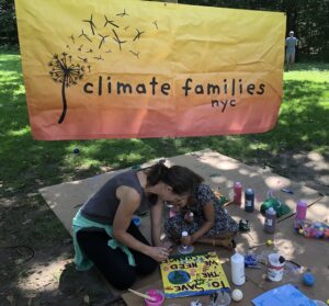 Woman and little girl in the park making signs for Climate Families NYC