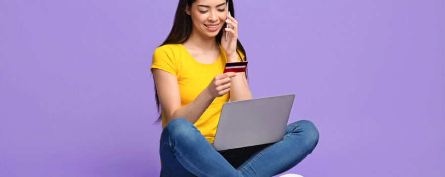 a young girl holding a credit card and with a laptop, included in an article about talking to your teen about credit