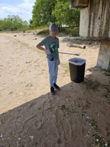 little boy at the beach on a sunny day collecting and disposing of litter, which he does on some NJ and Staten Island beaches