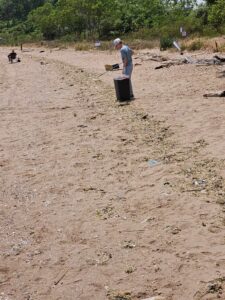 Little boy collecting trash on a sandy shoreline as he does on some NJ and Staten Island beaches
