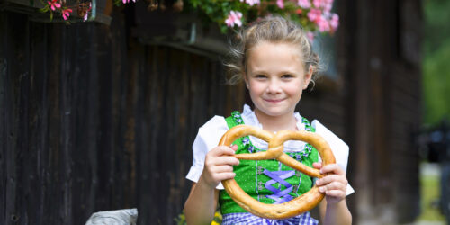 little girl holding a pretzel at a festival similar to celebrations of Oktoberfest on Staten Island and nearby