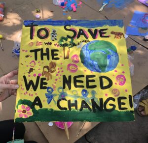 a sign that reads 'to save the world we need a change,' designed for Climate Families NYC