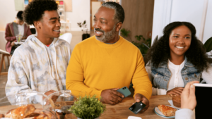 father holding a credit card in conversation with his two children at home, showing the importance of talking to your teen about credit