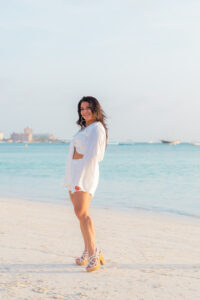 A woman, Betty Stallone, who supports Diva for a Day on Staten Island, on a beach wearing all white and white shoes.